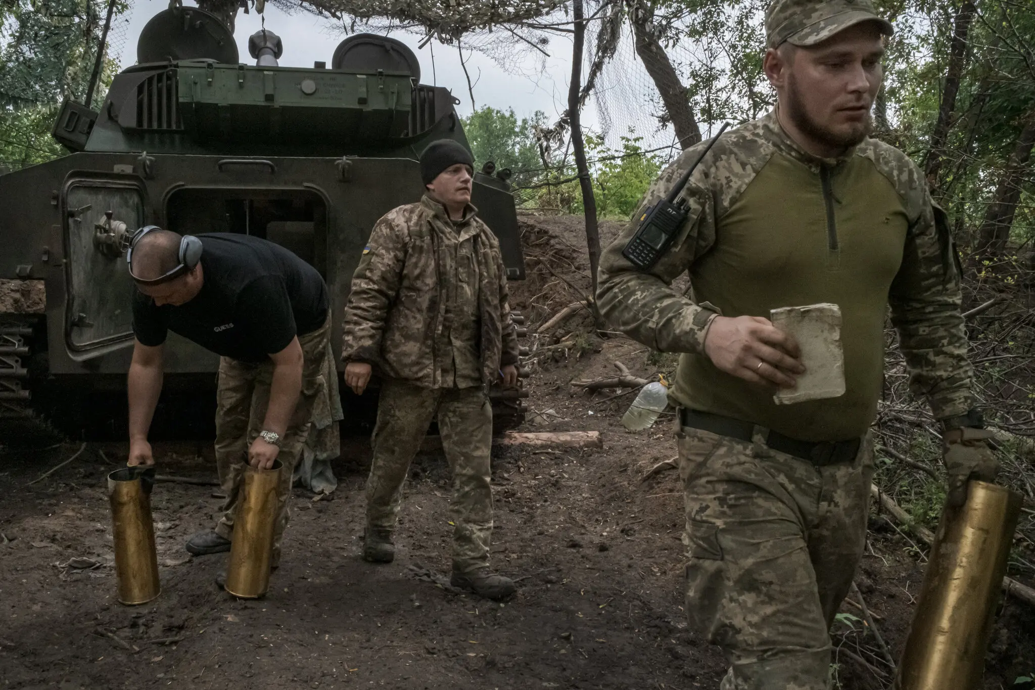 Українські військові збирають порожні снаряди після стрільби з самохідної гаубиці біля поля ферми в Донецькій області на сході України 26 червня.